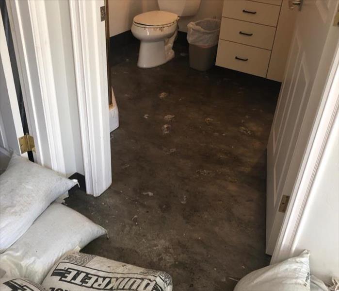 Toilet overflowed onto floor, sandbags keeping water in bathroom.