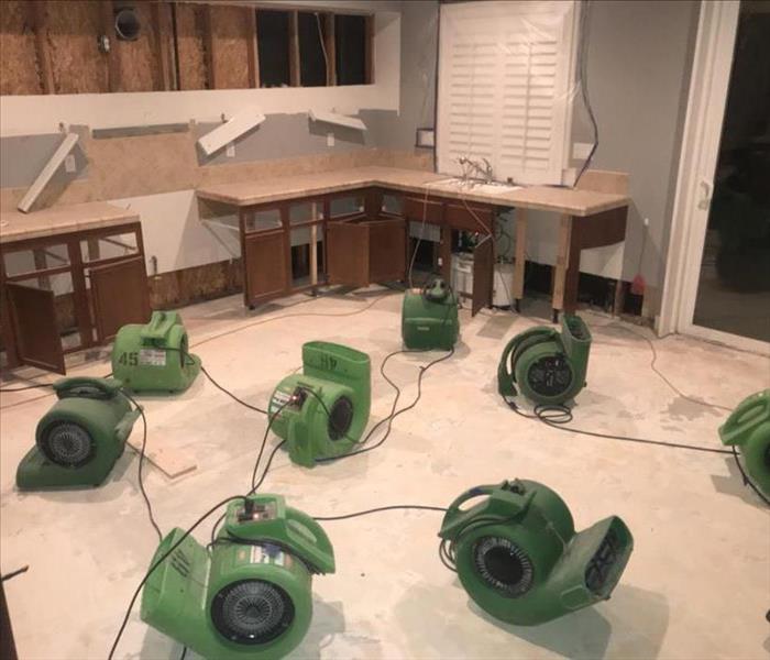 Room filled with air movers and dehumidifiers, drying water damage. 
